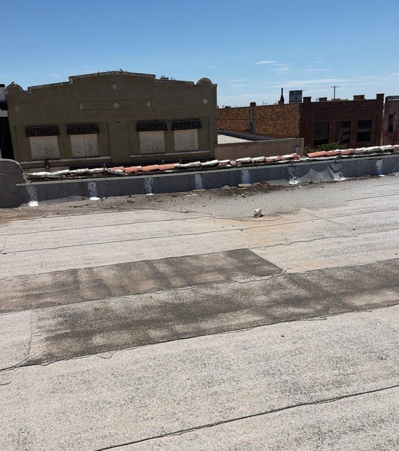 Wide view of a flat modified bitumen commercial roof membrane under bright sunlight