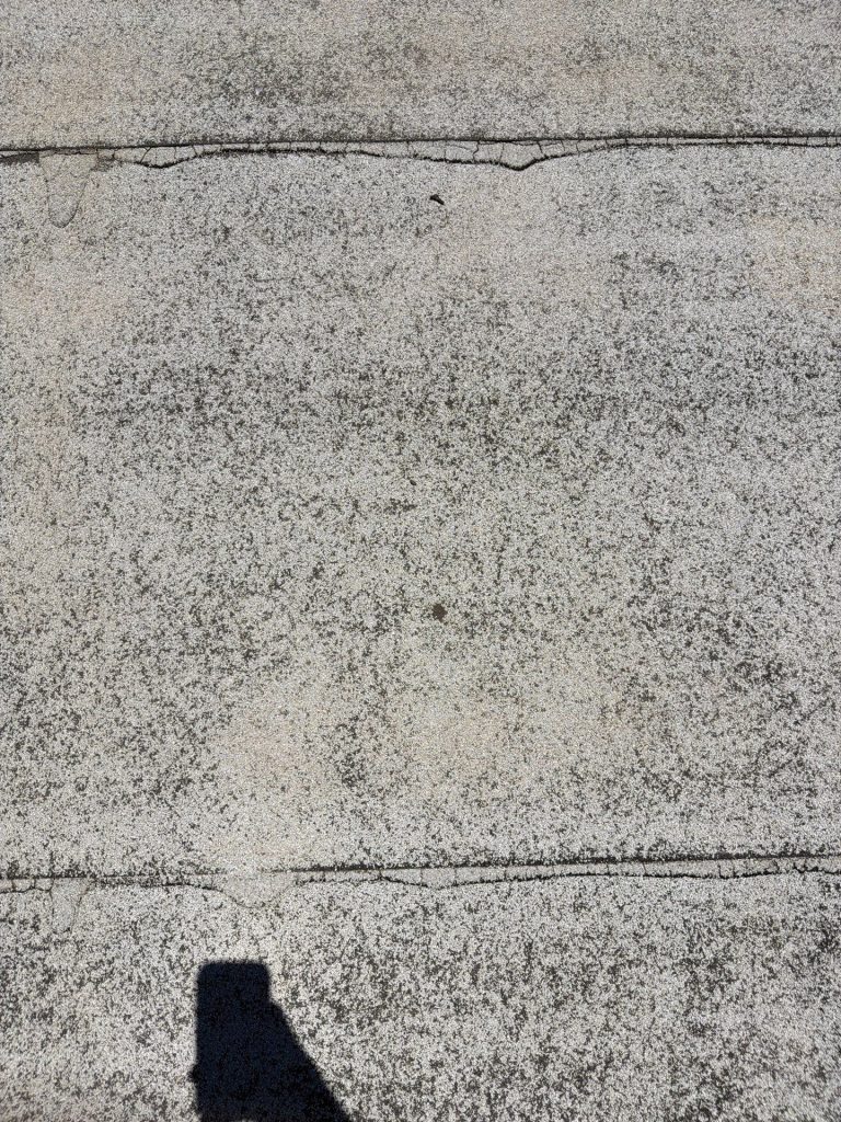 Close up inspection of wear and tear on a granular surface modified bitumen roof