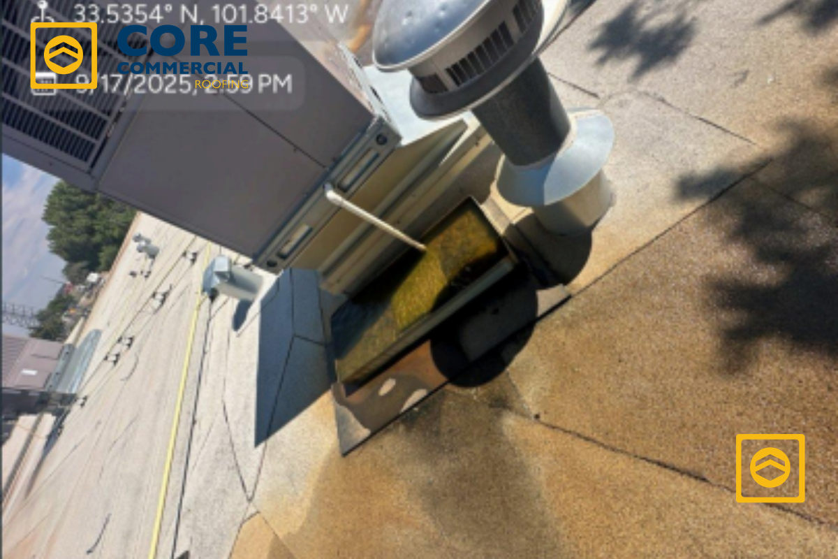 A secondary overflow pan full of standing yellow condensate water sitting beneath a commercial rooftop HVAC unit, causing a mechanical drainage issue.